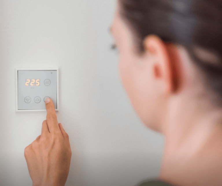 person changing temperature on thermostat